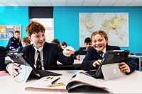 Description: Stamford School, Year 7 boy and girl pointing and laughing together at screens